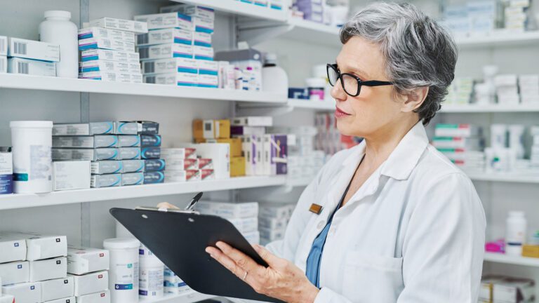 Pharmacy professional completing paperwork on a clipboard in the pharmacy