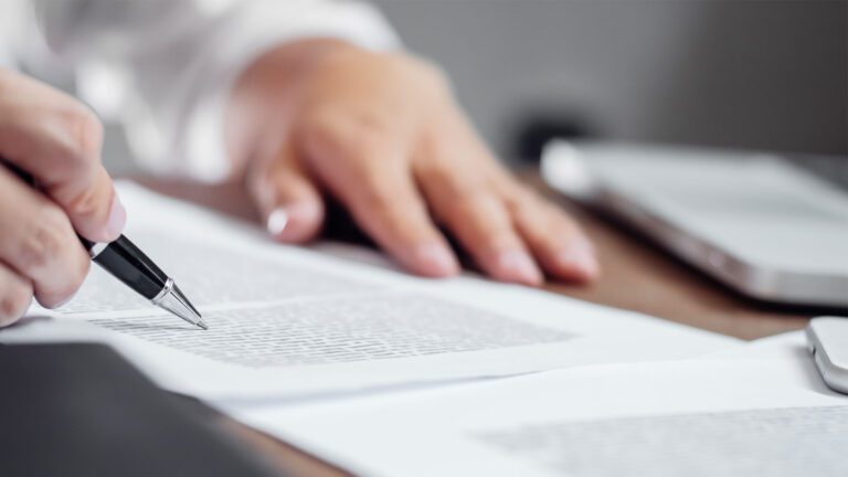 Closeup of individual completing and reviewing paperwork.